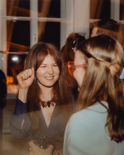 Eine formell gekleidete Gruppe von Menschen trifft sich zu einer Indoor-Party. Die lebhafte, festliche Atmosphäre ist perfekt für alle, die eine Weihnachtsfeier planen oder eine DJ Firma Weihnachtsfeier Österreich für eine unvergessliche Feier buchen möchten.